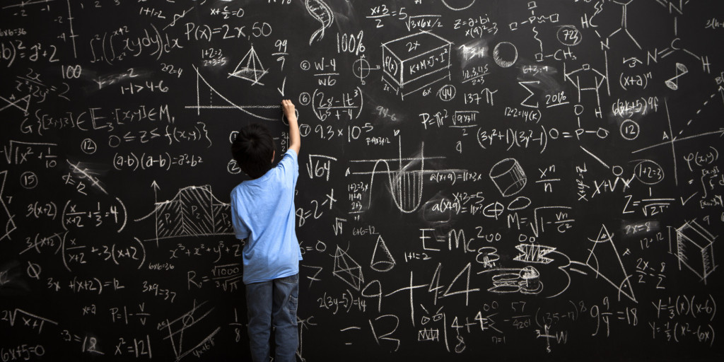 Young boy writes math equations on chalkboard